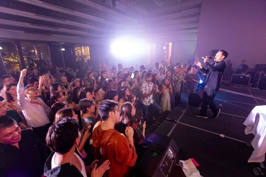 Live performer on stage engaging an excited crowd at a corporate dinner and dance event